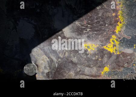 Metallic surface with dust, dirt and paint on the top. Part of element is covered in the dark shadow. Abstract detail Stock Photo