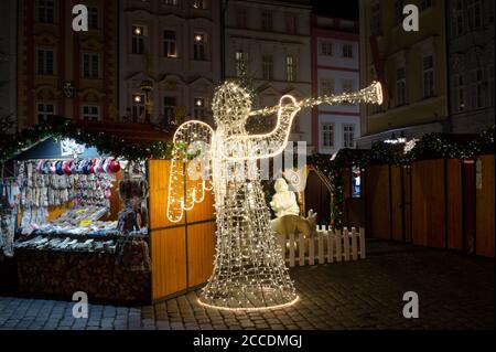 Christmas market on the square, Prague, Czech Republic / Czechia. Angel made of lights and bulbs, Exterior shop in the wooden booth and stand. Event d Stock Photo