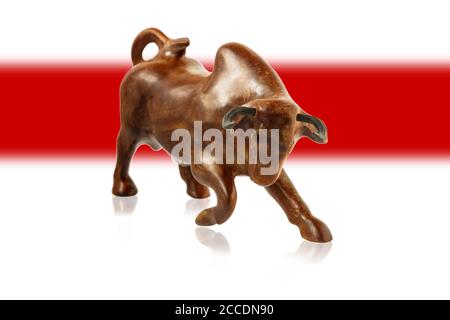 Wooden figure of a bull against the background of the white-red-white flag of Belarus. Stock Photo