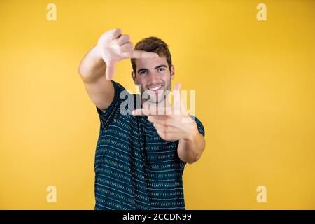 Young handsome man over yellow isolated background doing frame using hands palms and fingers, camera perspective Stock Photo