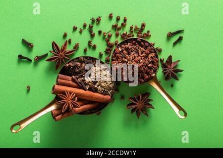 Food spices concept Organic Chinese five spice, cinnamon sticks, star anise, fennel seeds, Sichuan peppercorn and cloves in a copper cup on green back Stock Photo