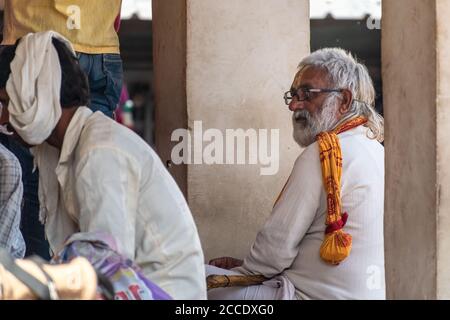 Orchha, Madhya Pradesh, India - March 2019: A portrait of an elderly male Indian pilgrim with a white beard and spectacles sitting inside a Hindu temp Stock Photo