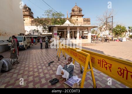 Orchha, Madhya Pradesh, India - March 2019: An elderly Indian male pilgrim sitting on the paved floor outside the ancient Hindu Ram Raja temple in the Stock Photo