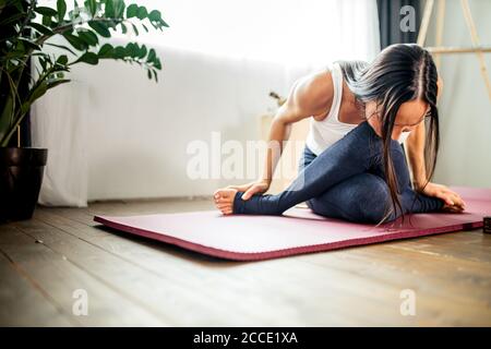 young and slender caucasian woman stretching at home, woman in sport clothes doing exercises at home during quarantine Stock Photo