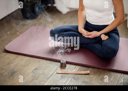 cropped photo of unrecognizable calm yogi female sit on the floor in lotus pose, meditate at home during quarantine, every morning begins from yoga, s Stock Photo