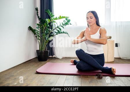young caucasian woman meditate with crossed legs, lady in sporty clothes keep calm, do yoga exercises indoors Stock Photo