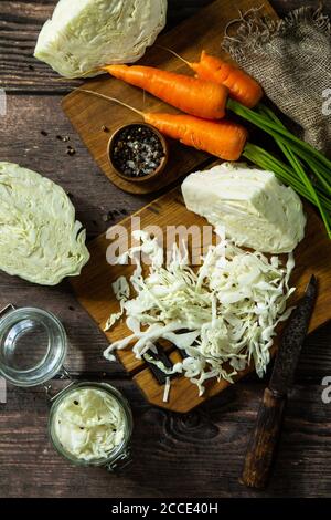 Fermented food. Prepare homemade sauerkraut jars with and carrot on rustic wooden table. Top view flat lay background. Stock Photo