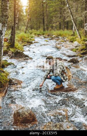 active tourist taking water into his cup from the river, full length side view photo Stock Photo