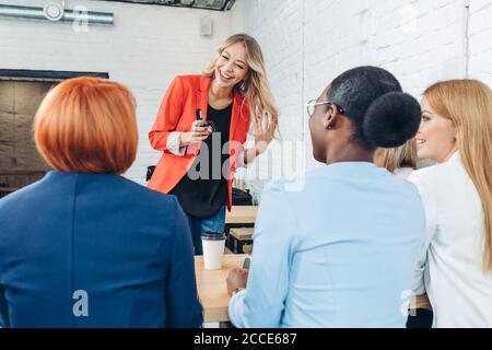 Blonde female employee make presentation for diverse co-workers during meeting in office cafe Stock Photo