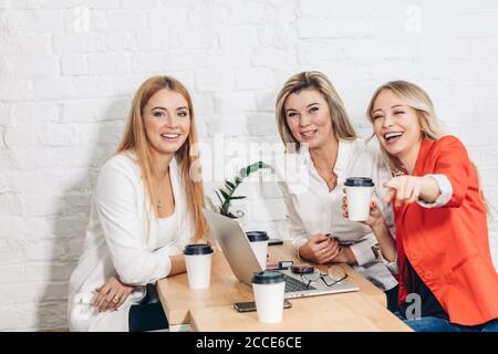 Group of female and male IT professionals working on software development using modern devices while sitting at table. Skilled bloggers are copywritin Stock Photo