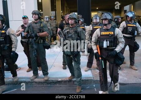 Tulsa, OK, USA. 20th Jun 2020 Police officers stand by as a crowd protesting President Donald Trump's rally march by.
