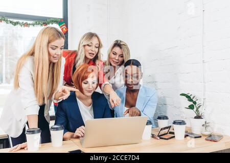 Red-haired teacher explaining new material on economics to her beautiful female students, while having lesson at cafe. People and education concept. Stock Photo