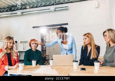 African female Executive scolding a shameful employee at work in an office meeting Stock Photo