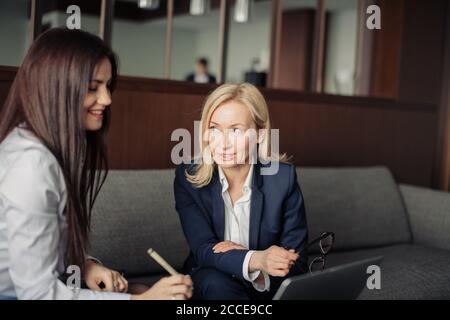 Two caucasian female coworkers working together on business project using laptop, female executive explaining new online idea to coworker at office Stock Photo