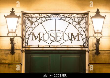 Museum sign over entrance door. Museum entrance lit up at night. Stock Photo
