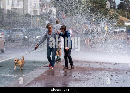 People walking a dog in Southend on Sea, Essex, UK, during the high winds of Storm Ellen, getting wet from crashing wave. Road, cars, traffic Stock Photo