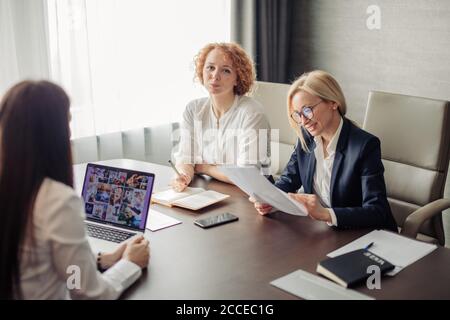Group of two female corporate mentors check the knowledge of the woman trainee at the end of the trial period Stock Photo