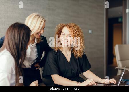Portrait of three successful young attractive elegant business woman collaborating together in office. Stock Photo