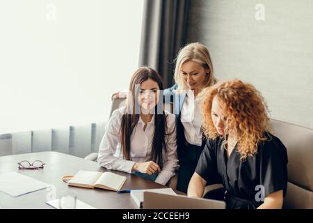 beautiful clever cute charming attractive elegant female business partners have online meeting with potential investor, gather in circle near table wi Stock Photo