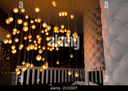 Stylish rich decor of the room is a chandelier made of many glowing balls. Stock Photo