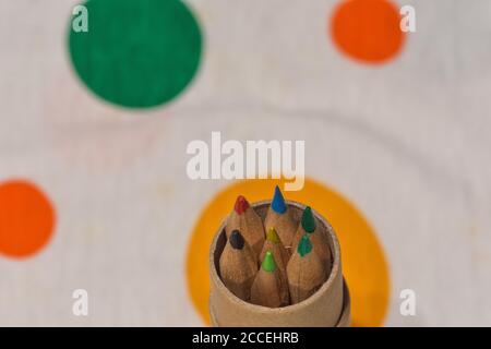 Colored pencils inserted in a cardboard cylinder on a colored plane, horizontal image Stock Photo
