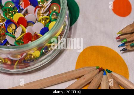 colored thumbtacks in a glass jar and colored pencils Stock Photo