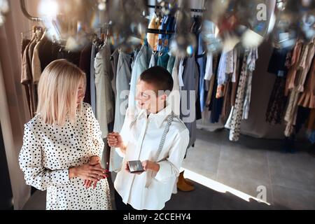 Top shot of professional dressmaker discuss with client about new dress. Creating new clothes. Blonde model and caucasian clothes designer Stock Photo