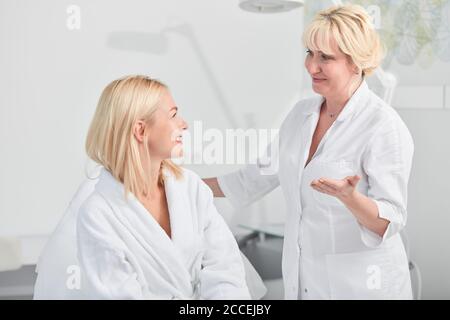 friendly conversation between a client and a doctor before procedure, therapist preparing a patient for a treatment Stock Photo