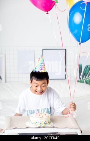 excited asian boy looking at the cake with candles , happy birthday party. close up photo. happiness Stock Photo