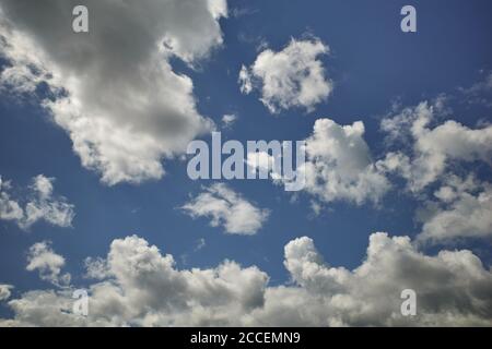 Fluffy cumulus clouds in the glorious blue sky. Sunlit heaven. Background for forecast and meteorology illustration Stock Photo