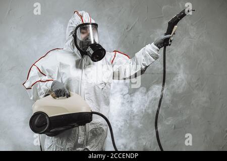 disinfector in a protective suit conducts disinfection in contaminated area. professional disinfection against COVID-19, coronavirus. in clothing prot Stock Photo