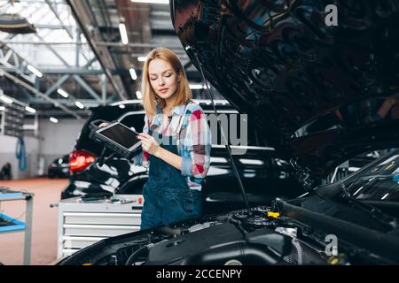 good looking girl holding a tablet and examining the car, close up photo, copy space Stock Photo