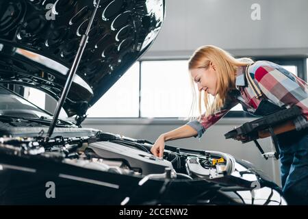 blond girl enjoying monitoring a car at the garage. close up side view photo Stock Photo