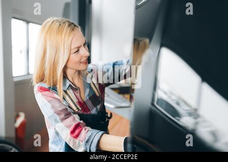 young fair-haired female mechanic having fun in the garage. close up side view photo. Stock Photo