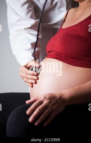 Doctor listening to foetus's heartbeat Stock Photo