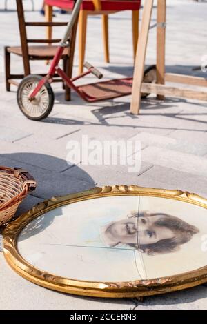 Old colored black and white photo of a toddler in a broken gold frame at a flea market Stock Photo