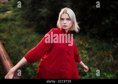 Nude in the forest: a backlit young naked blonde woman girl standing in