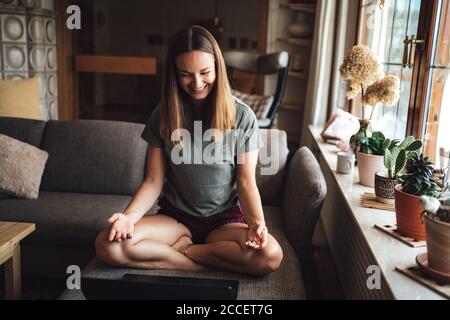 Happy Caucasian young woman having video conference call via laptop with friend at home Stock Photo