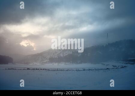 Snowy landscape where the sun's rays pass through deep clouds Stock Photo