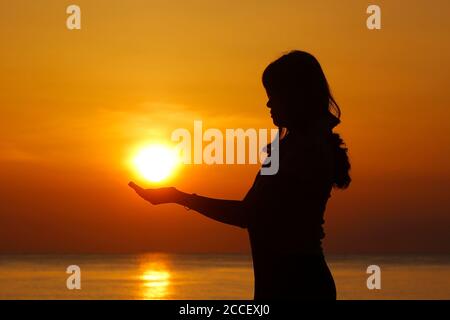 silhouette of female holding sun on the beach Stock Photo - Alamy