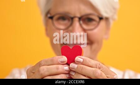 Close up. Happy senior woman showing the heart shape between her fingers. Emotion love and support concept. High quality photo Stock Photo