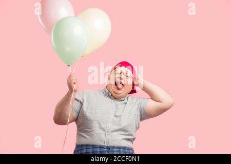 Funny adorable tubby animator, man from mini club, with vivid emotions looking cheerful, smiling happily, posing at camera, holding air balloons isola Stock Photo