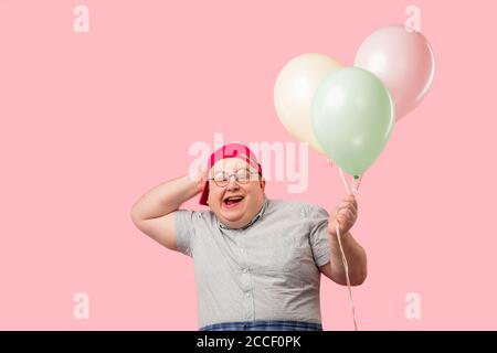 Happy funny emotional man in his 30s dressed in grey t-shirt tucked into plaid pants being overjoyed and enthusiastic about his good joke with air bal Stock Photo