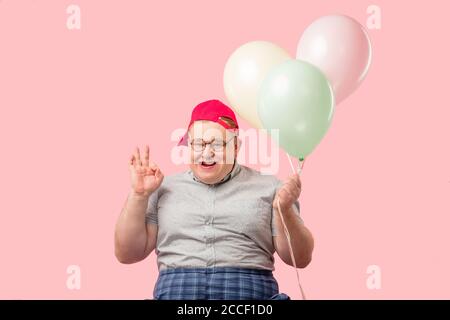 Happy funny emotional man in his 30s dressed in grey t-shirt tucked into plaid pants being overjoyed and enthusiastic about his good joke with air bal Stock Photo