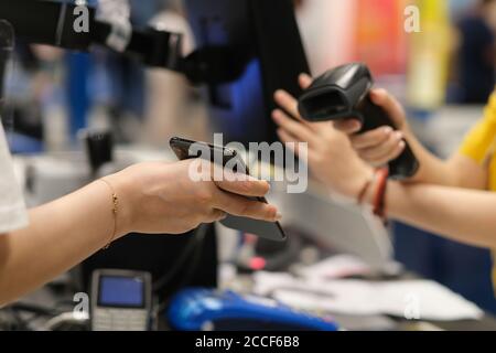 close up hand holding phone to scan to pay at checkout. contactless payment. soft focus Stock Photo