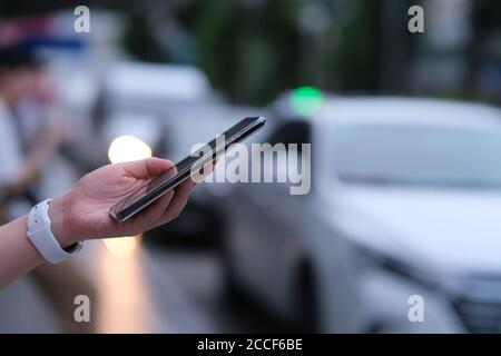 close up hand using smart phone on the street. blurred cars background Stock Photo