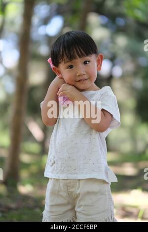 close up one cute Asian toddler holding toy at park, looking at camera Stock Photo