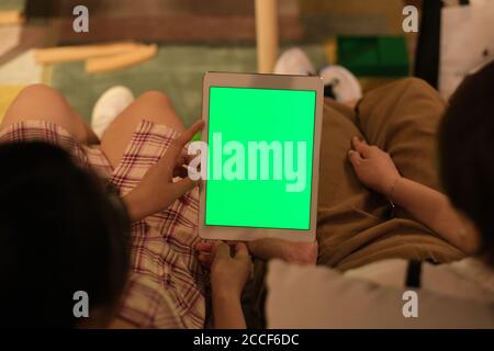over shoulder view of two women looking at green screen tablet together at home Stock Photo