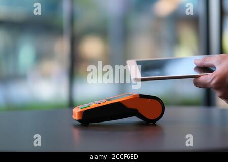 close up people using digital tablet to pay over pos terminal on table. blur background Stock Photo