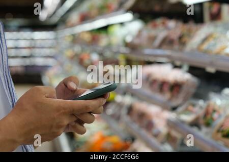 close up hands using smart phone at grocery store Stock Photo
